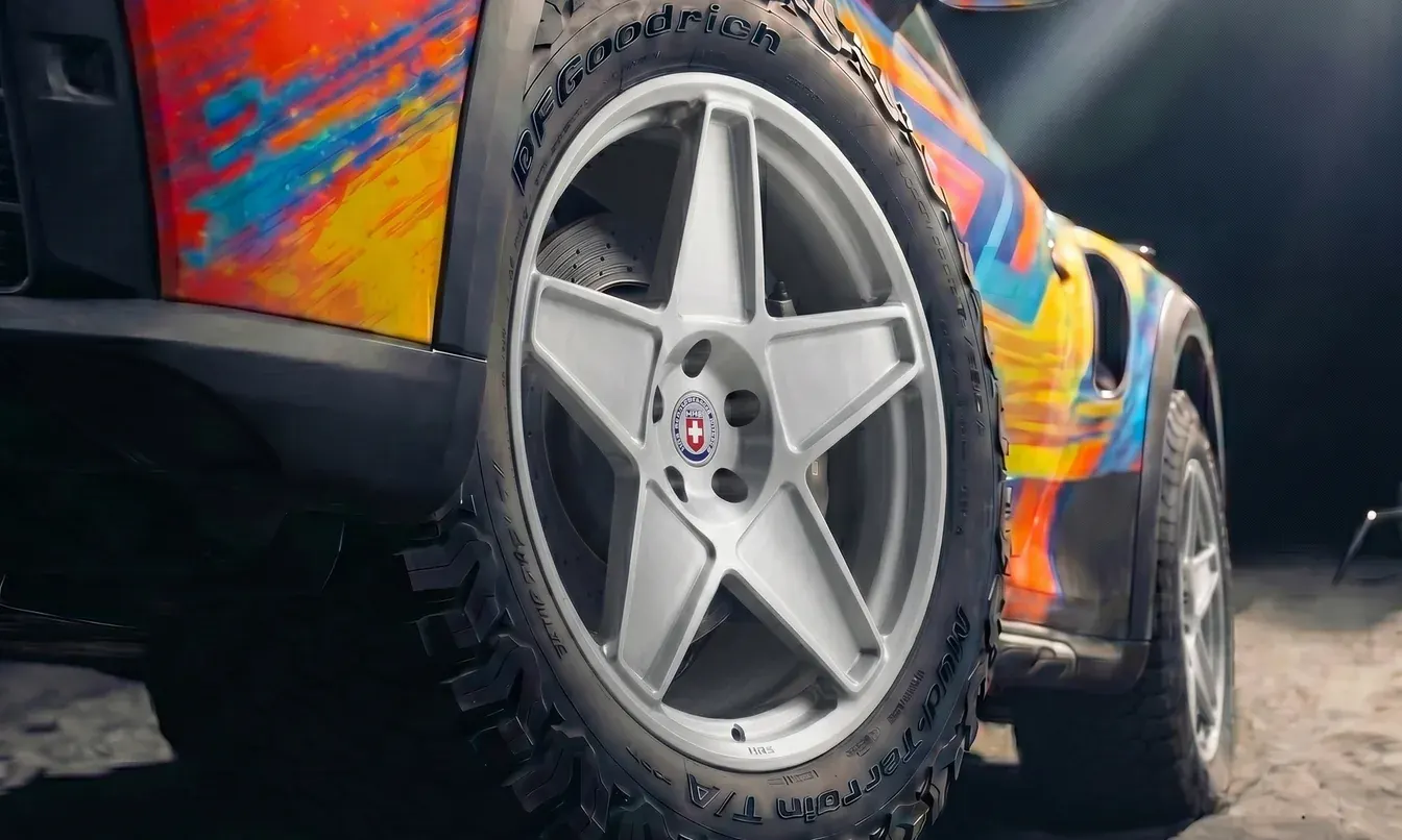 Colorful Porsche off-road build close-up with silver HRE five-spoke wheels and all-terrain tires