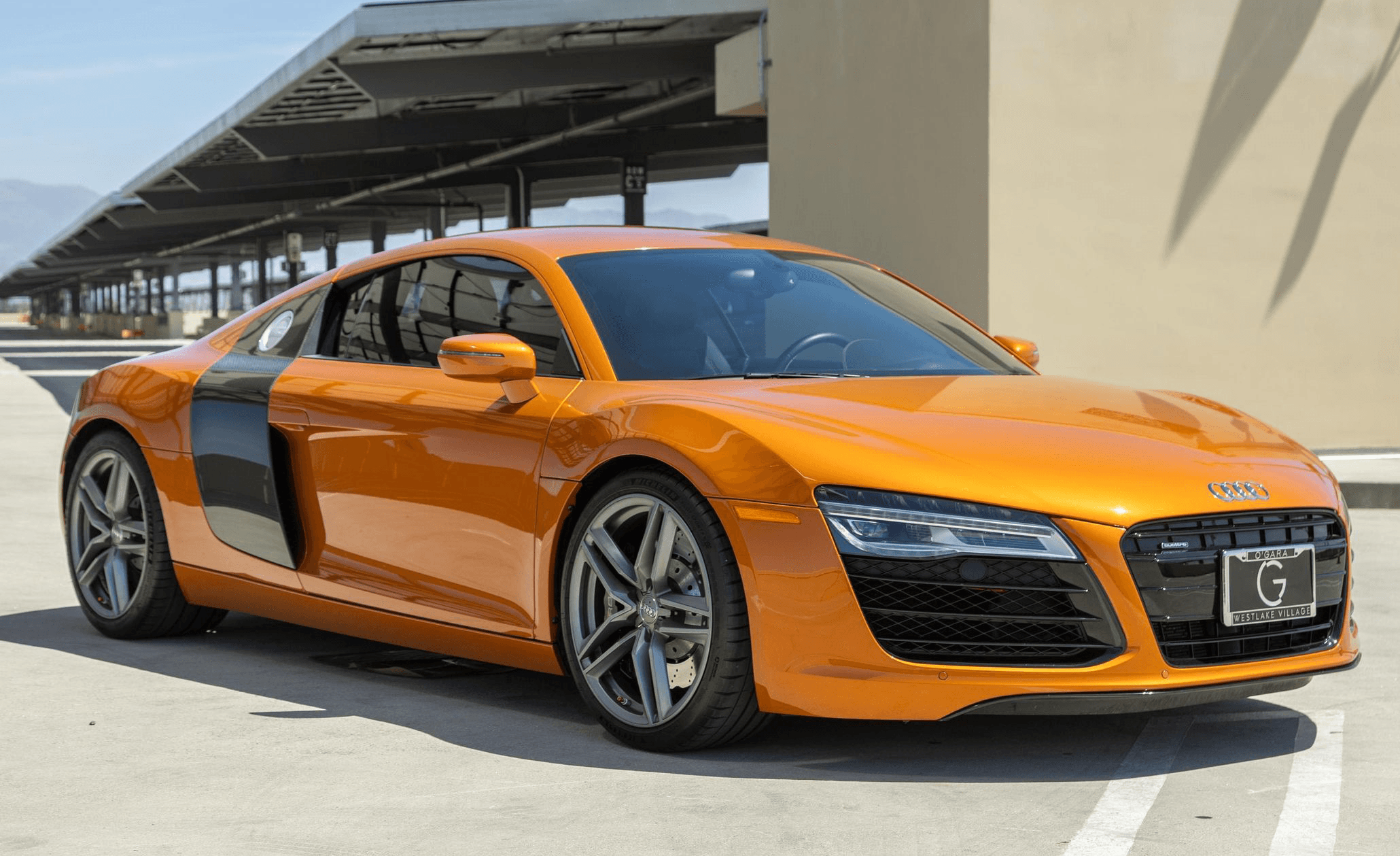 Orange Audi R8 (first gen) front three‑quarter with carbon side blade in a parking structure