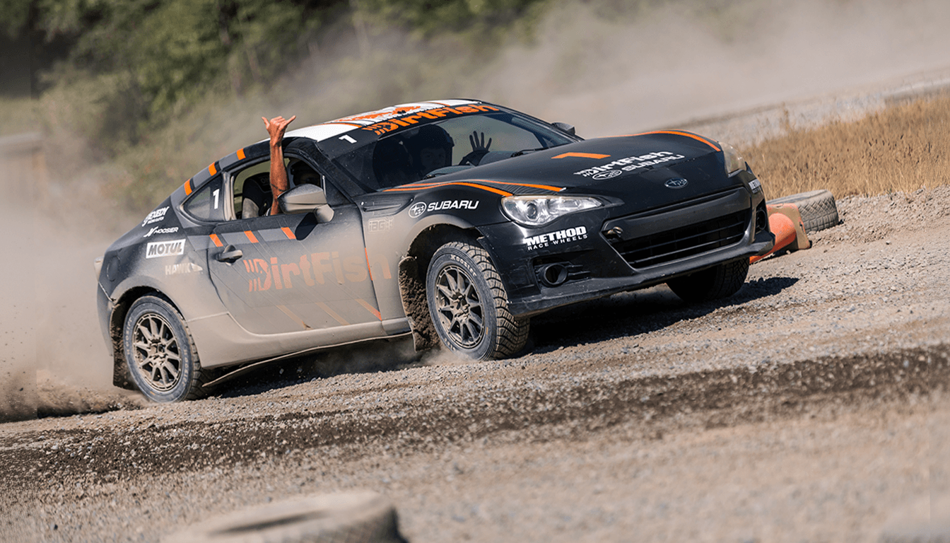 DirtFish‑liveried Subaru BRZ sliding on a gravel rally course