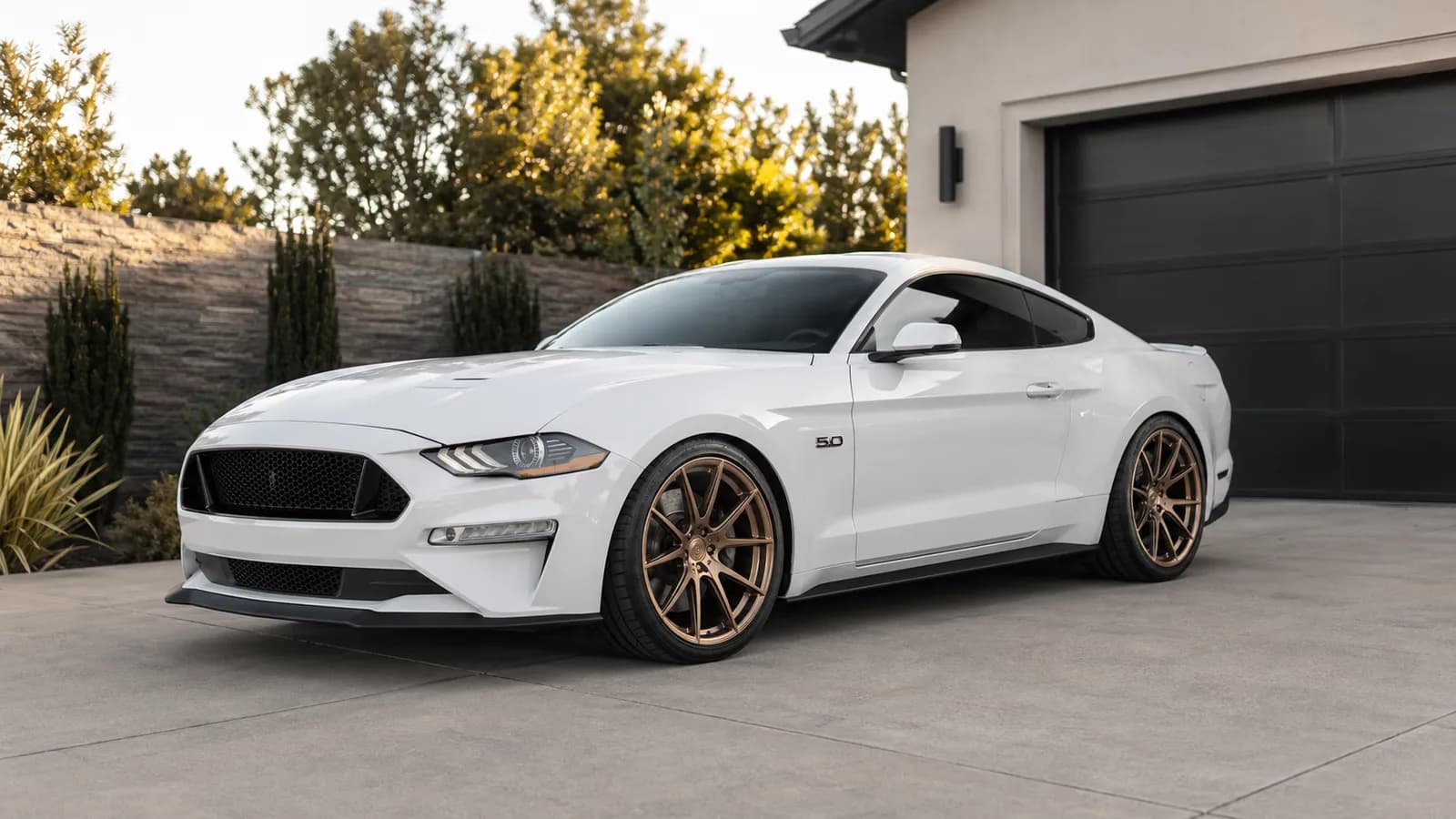 White coupe with bronze aftermarket wheels in a driveway for virtual wheel fitment preview