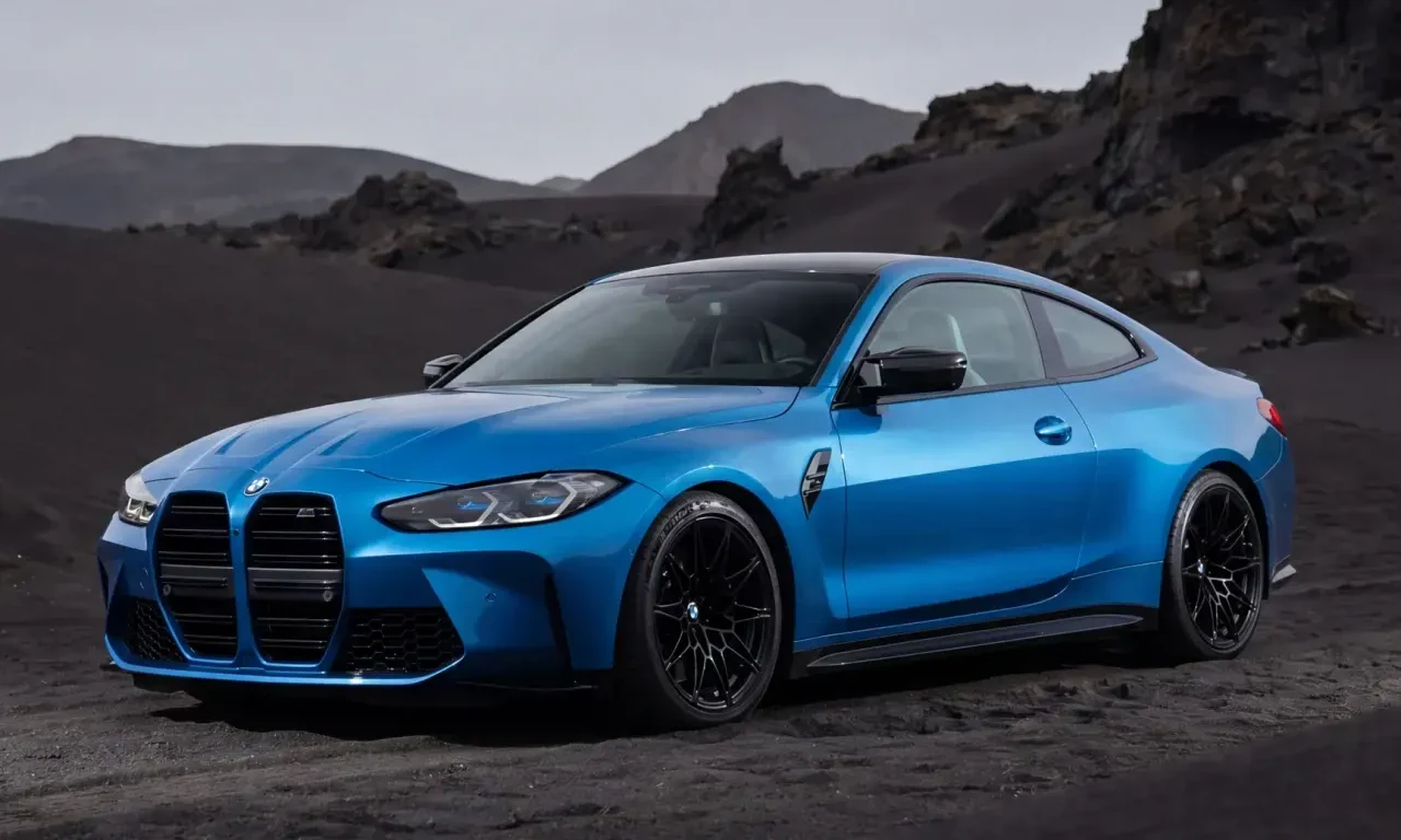 Blue BMW M4 coupe on black volcanic sand with dark factory wheels
